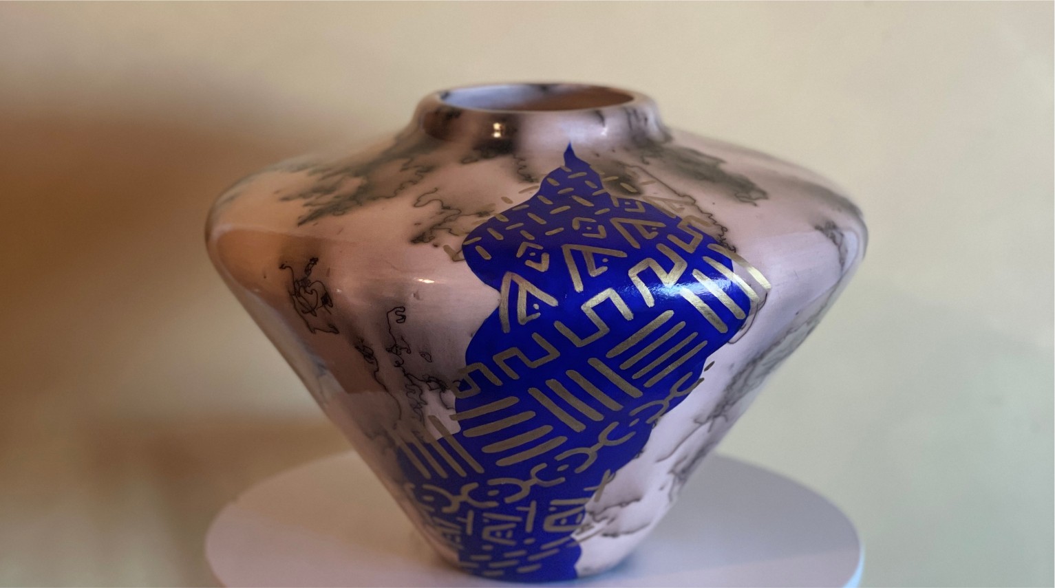 A horsehair-fired vessel with smoke markings and a cobalt blue panel hand-painted with gold mudcloth designs